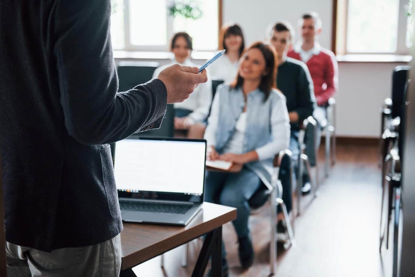 Eine Gruppe von Arbeitnehmern sitzt in einem Seminarraum und nimmt an einer betrieblichen Weiterbildung teil.