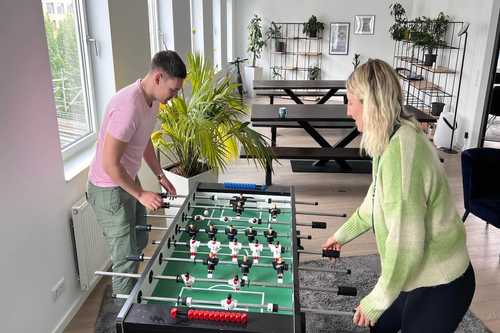 Zwei Personen spielen im Büro Kicker, ein beliebtes Beispiel für Corporate Benefits für Mitarbeiter.